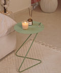 Angolo modern side table with a green top, candle, and decorative items styled in a contemporary living room.