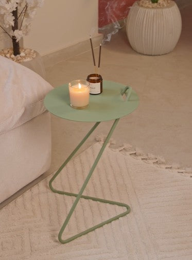 Angolo modern side table with a green top, candle, and decorative items styled in a contemporary living room.